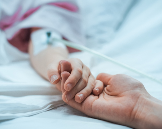 maminka drží ruku dítěte v nemocnici s vrozenou malformací 