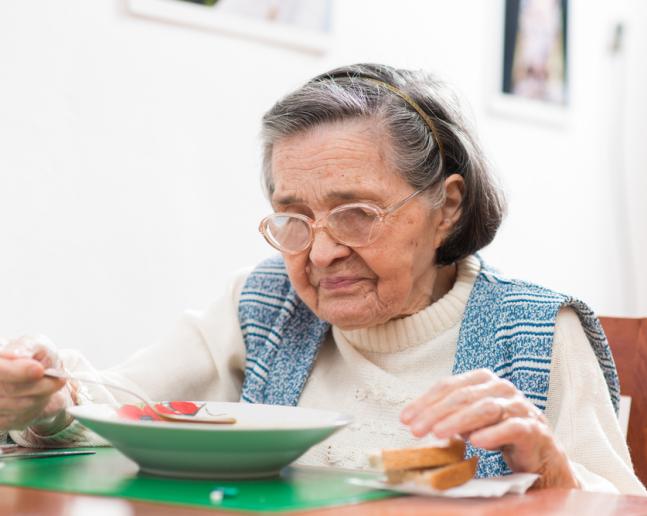 Seniorní žena jí oběd a má malnutrici 
