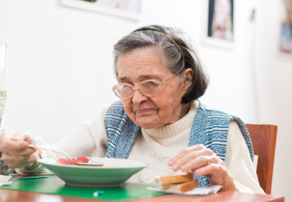 Seniorní žena jí oběd a má malnutrici